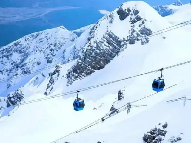 Blaue Seilbahnen fahren über schneebedeckte Gipfel am Jade-Drachen-Schneeberg.